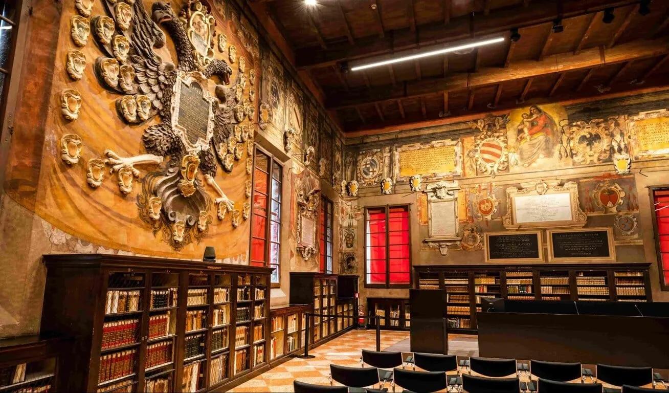 Interior of a historic library with ornate decorations, large wall relief of an eagle, and shelves filled with old books.