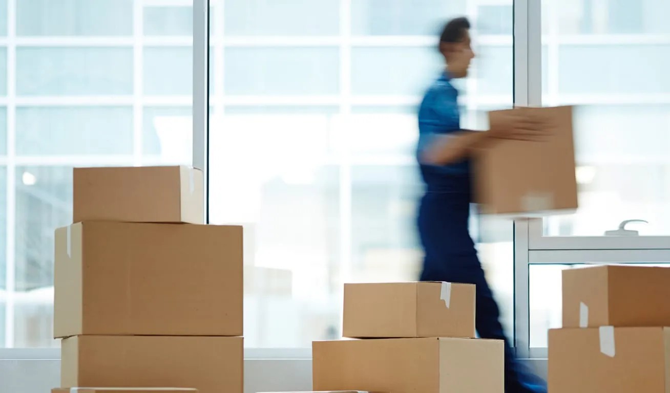 Busy Mover - Active Relocation Blurred mover carrying boxes in front of a glass building