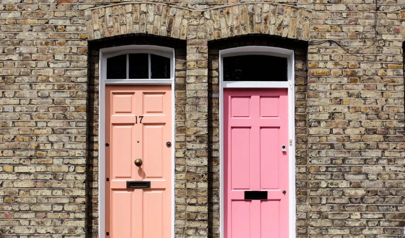 Colorful Entryways - Contrasting Doors Two doors, one peach and one pink, in a brick wall